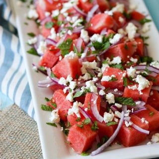 watermelon mint feta salad on white rectanuglar plate on bright blue background