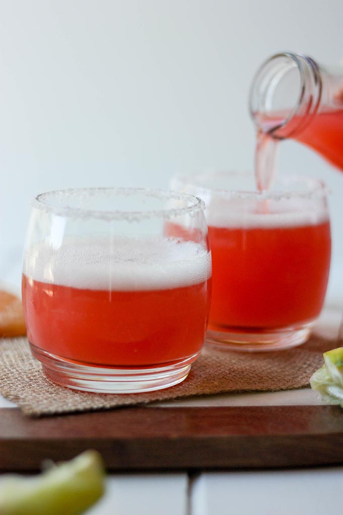 grapefruit juice being poured into two glasses of grapefruit margaritas