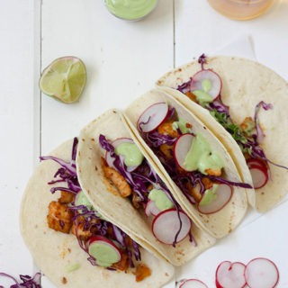 4 healthy fish tacos lined up on a white board
