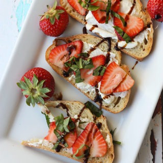 white plate lined with pieces of strawberry bruschetta