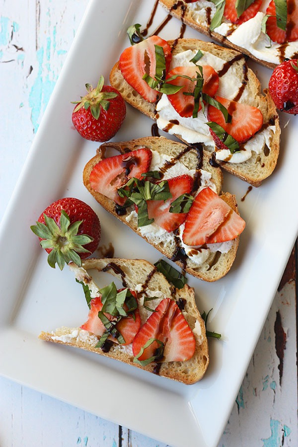 white plate lined with pieces of strawberry bruschetta