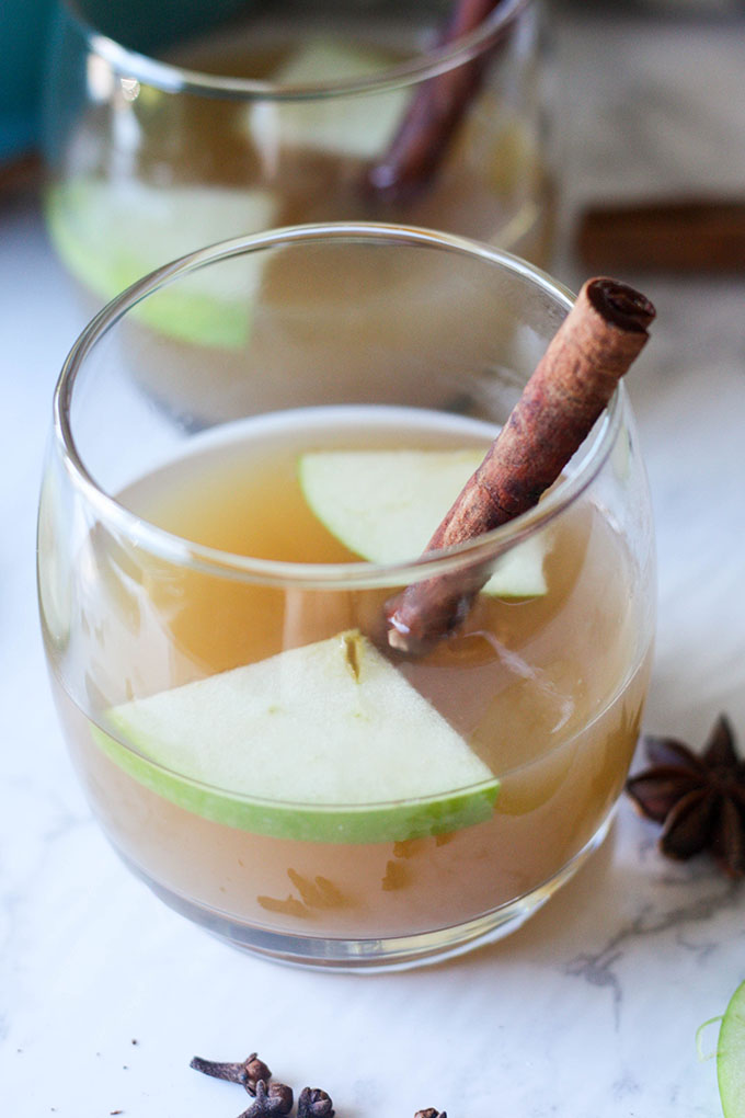 hot spiced apple cider in glass with cinnamon quill