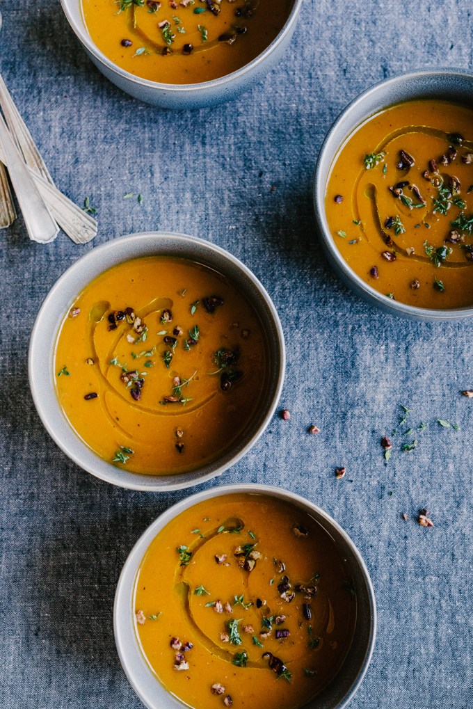 four bowls of pumpkin apple soup on a blue board