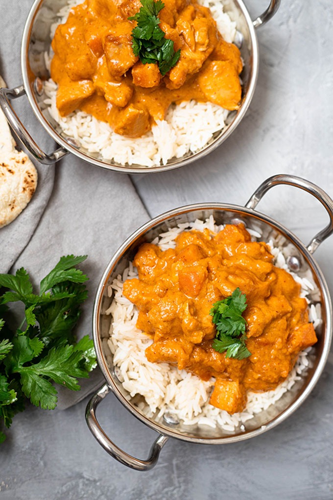 two dishes of chicken massaman curry in copper dishes