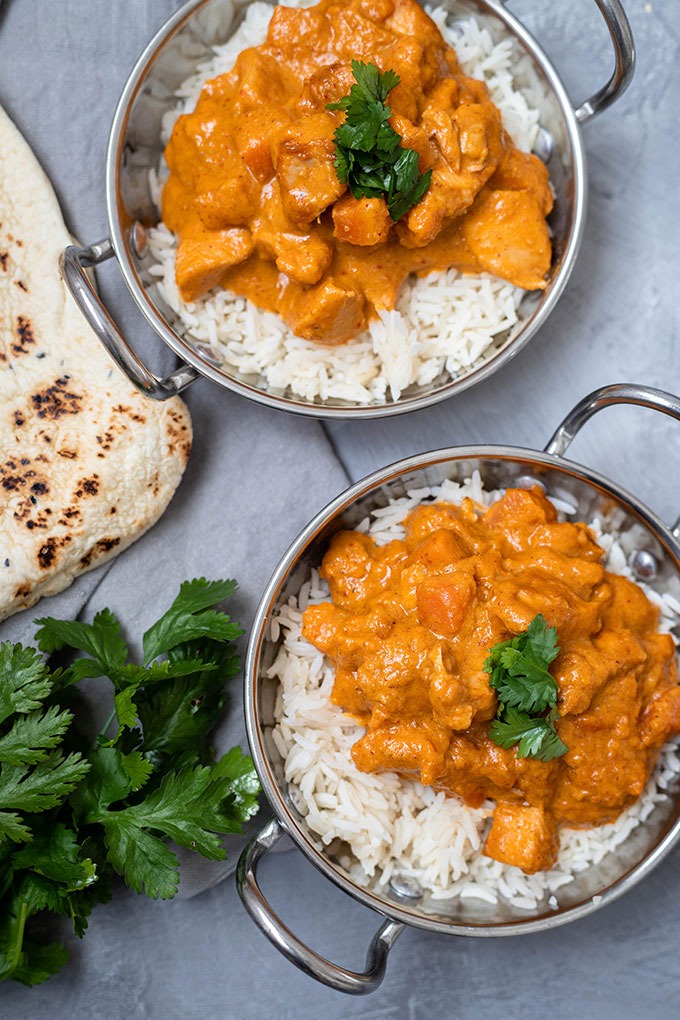 two dishes of chicken massaman curry on grey board