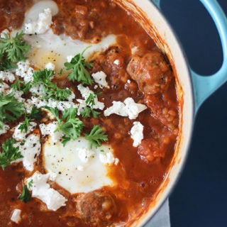 blue dutch oven with spicy shakshuka and meatballs on blue board