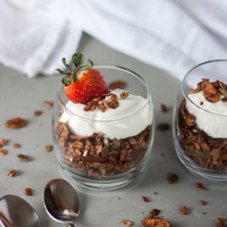 glass pot of chocolate granola topped with yogurt and berries