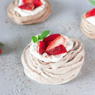 close up chocolate meringue nest with whipped cream and strawberries