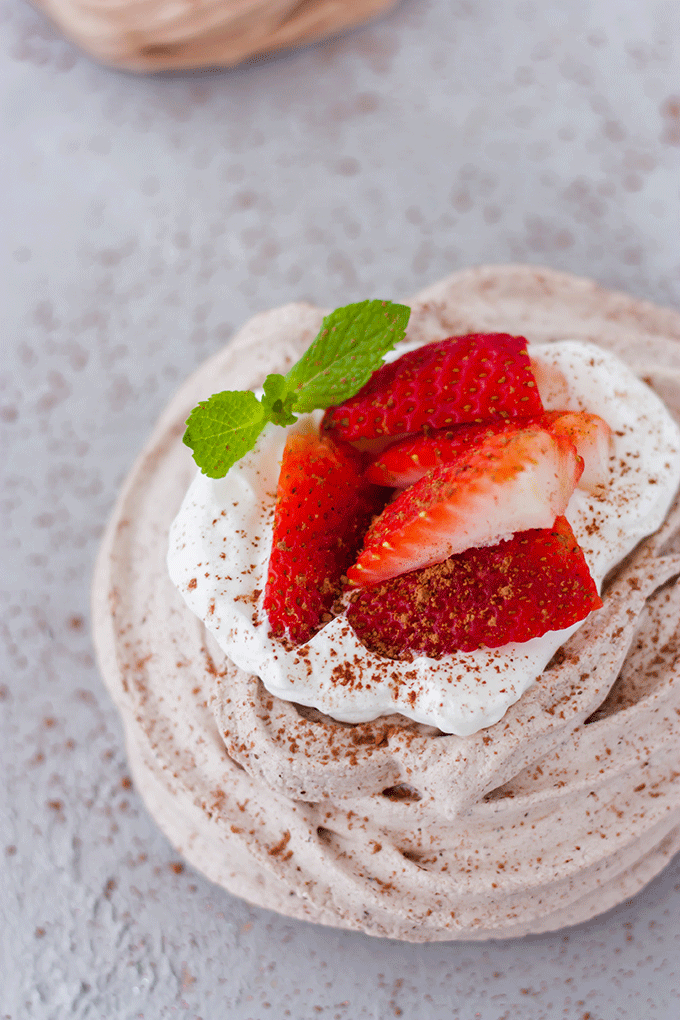 overhead chocolate meringue nest with whipped cream, strawberry and mint garnish