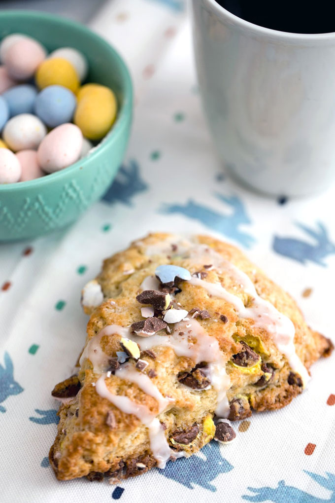 a chocolate scone on a colourful plate with mini eggs in background