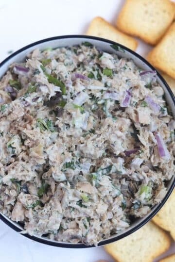 salmon dip in bowl surrounded by mini toasts.