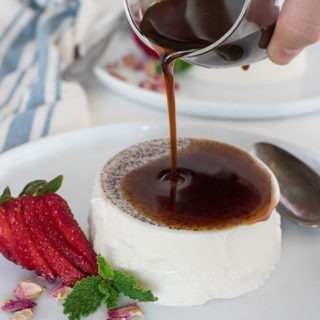 espresso syrup being poured over a vanilla bean panna cotta on white plate