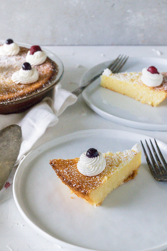 piece of lemon coconut tart on two white plates with antique fork