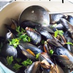 rose wine mussels in a blue dutch oven with text on top of image for Pinterest