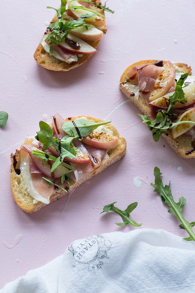 three slices of bruschetta laid out on pink board with a white napkin