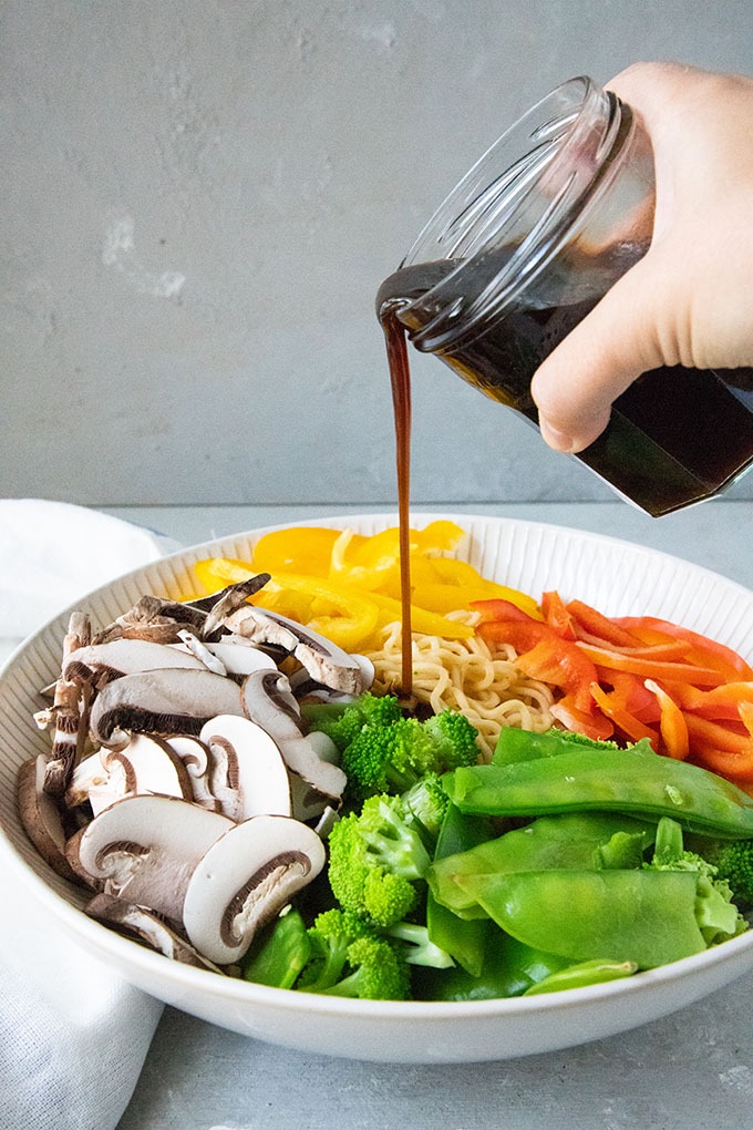 salad dressing being poured into asian noodle salad 