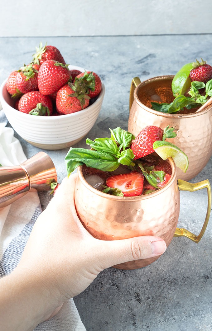 hand reaching out to grab strawberry basil mule mug