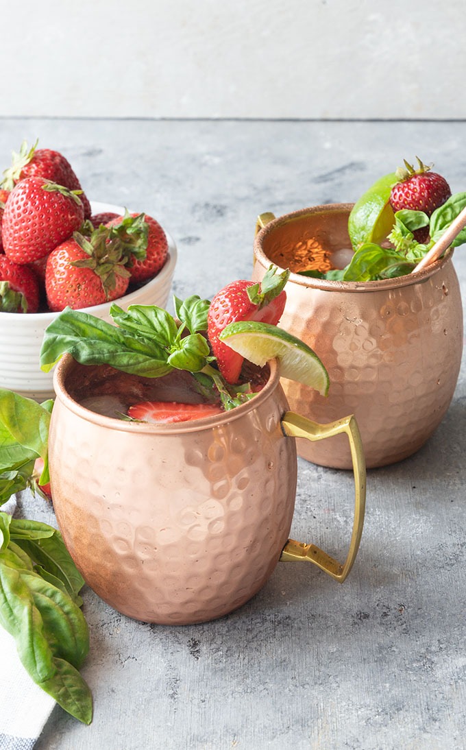 two strawberry basil mule mugs on grey board