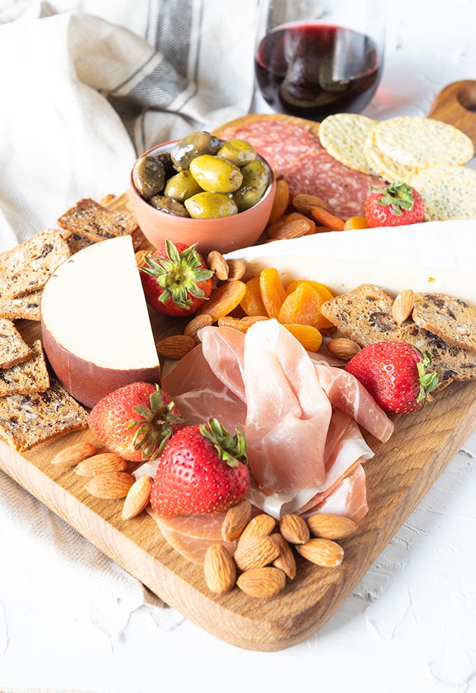 meat and cheese board featured with glass of red wine