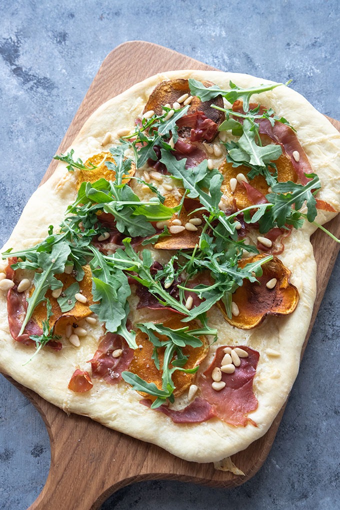 uncut butternut squash pizza on wooden board