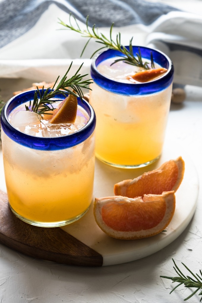 two grapefruit gin cocktail glasses on white marble board