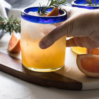 hand reaching out to grab a grapefruit gin cocktail