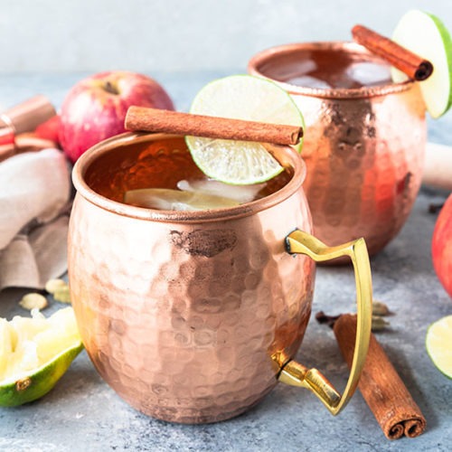 two copper mugs of apple cider moscow mule