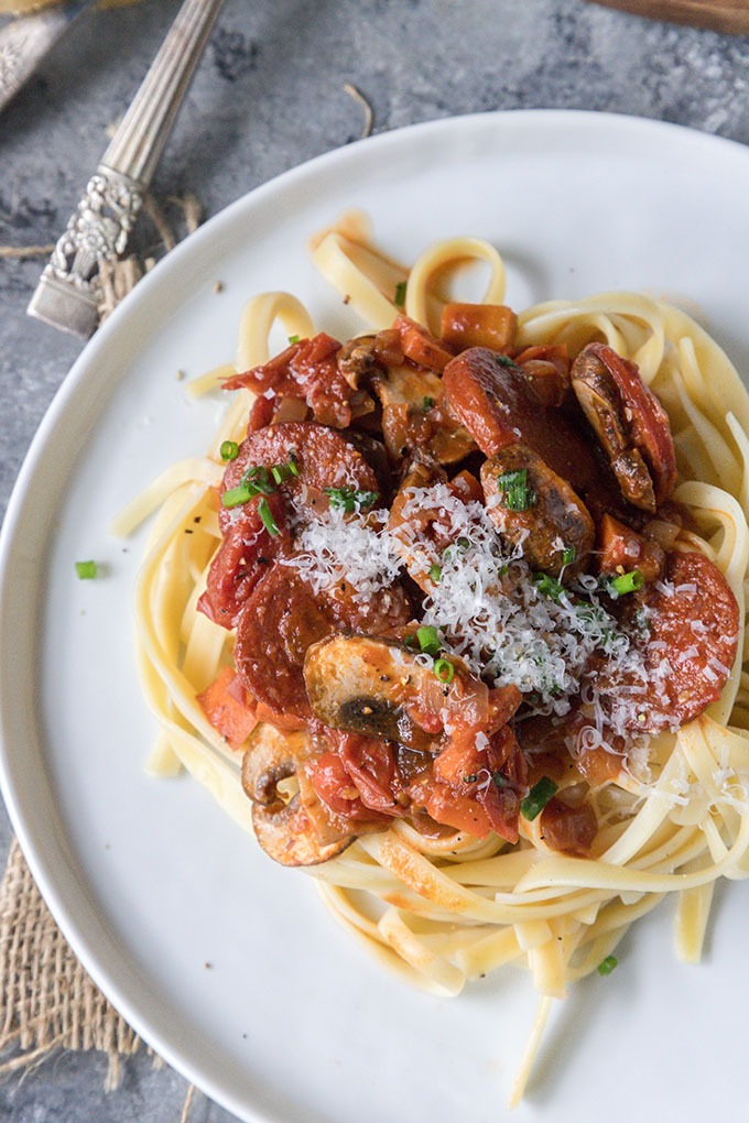 tomato chorizo pasta on white plate close up image
