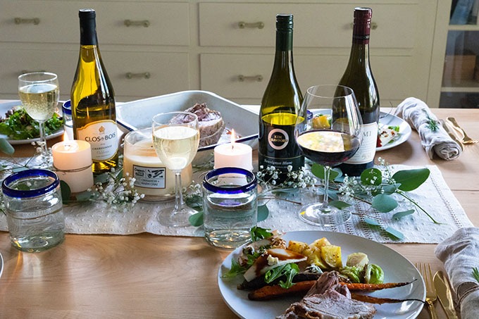 table set out with wine, boneless lamb roast and sides