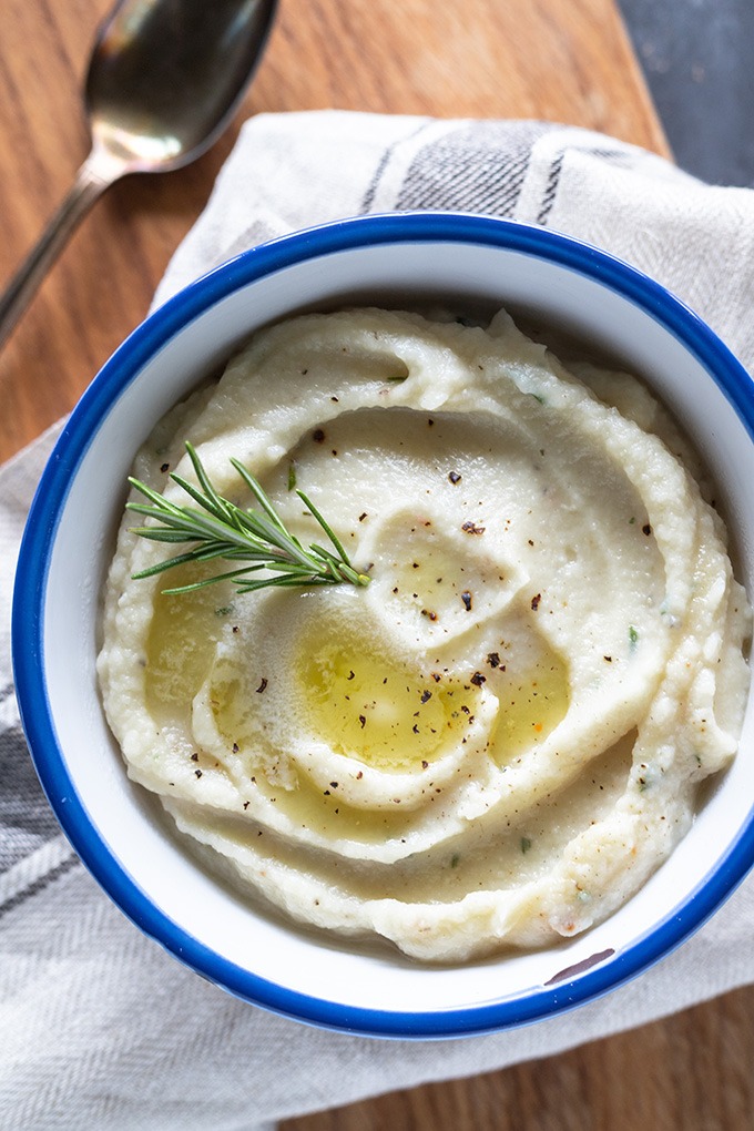 creamy mashed cauliflower in a white bowl with blue rim