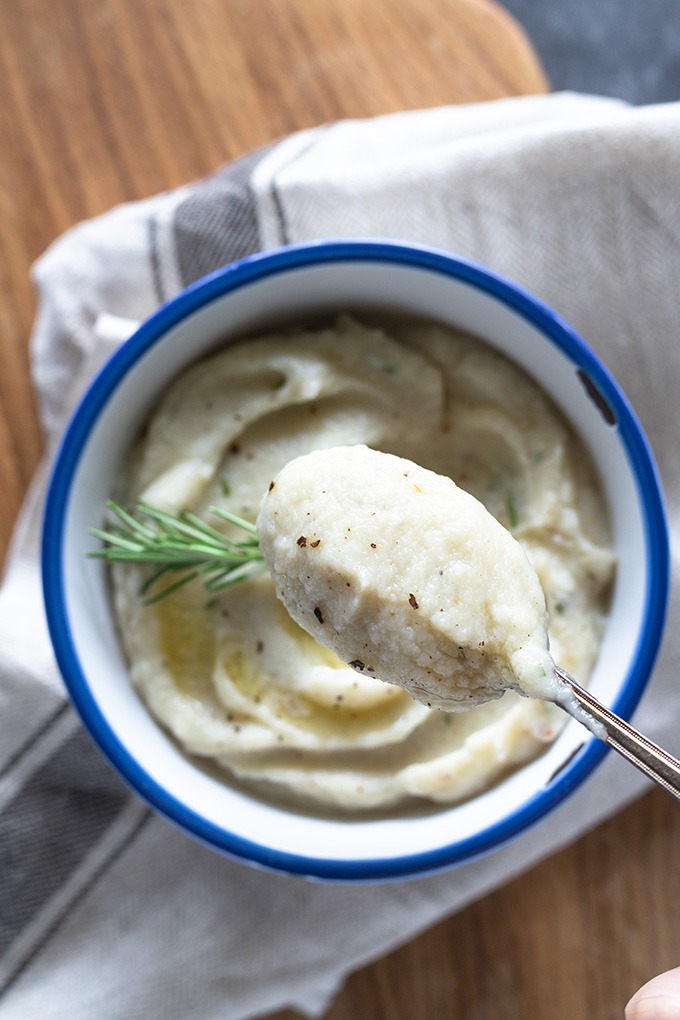 spoon of cauliflower mash over white bowl with blue rim