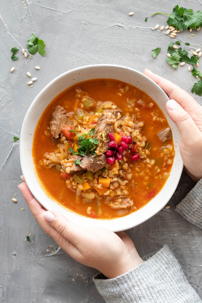 hands holding bowl of lamb shank soup 