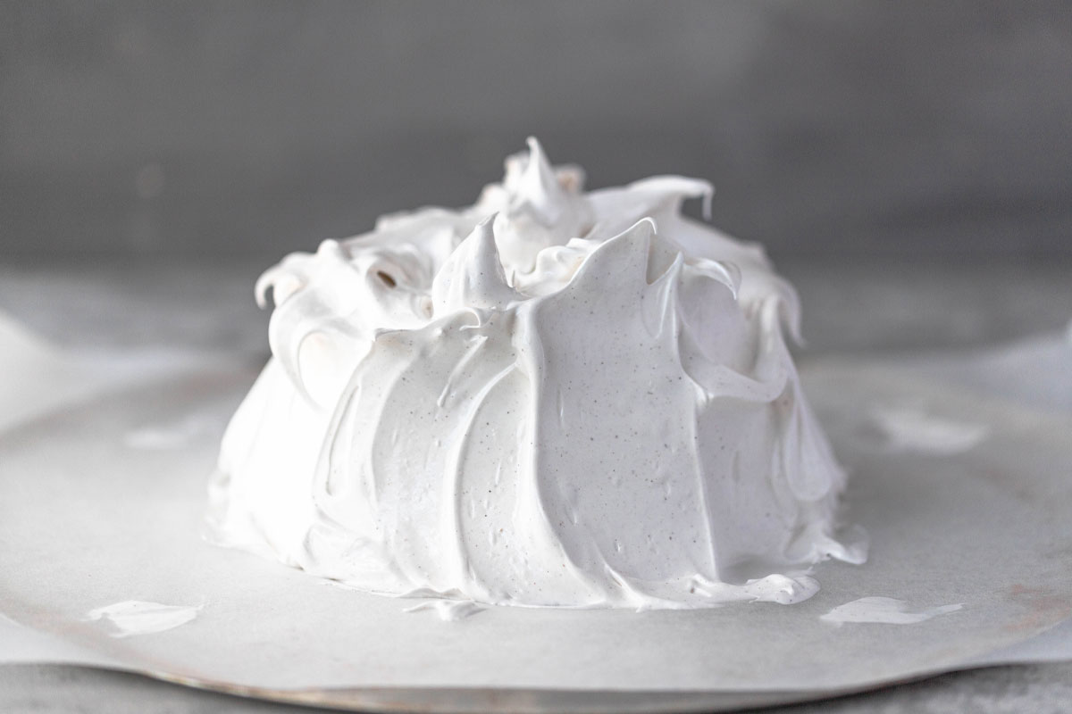 unbaked pavlova shaped on a piece of baking paper with soft peaks