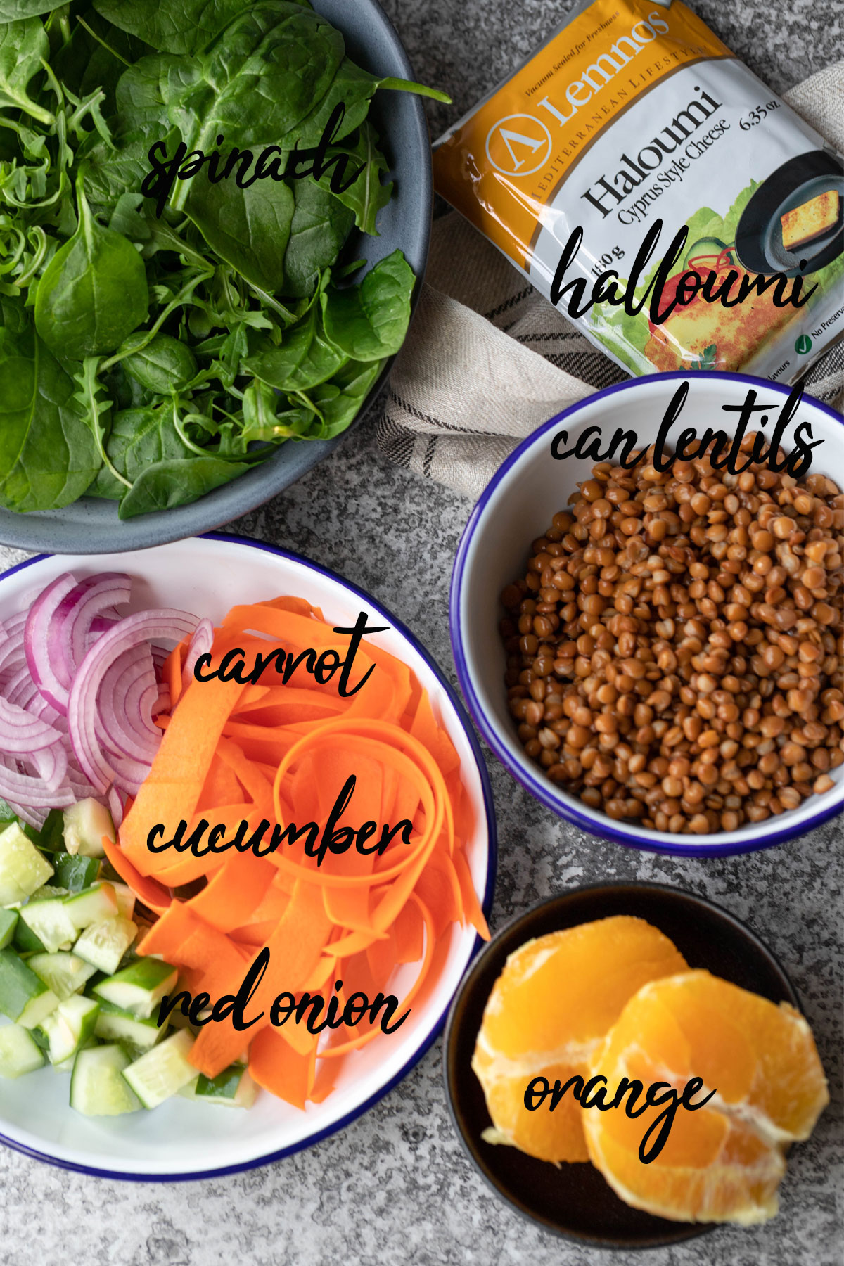 lentil halloumi salad ingredients from top - spinach, halloumi, can lentils, carrot, cucumber, red onion and orange