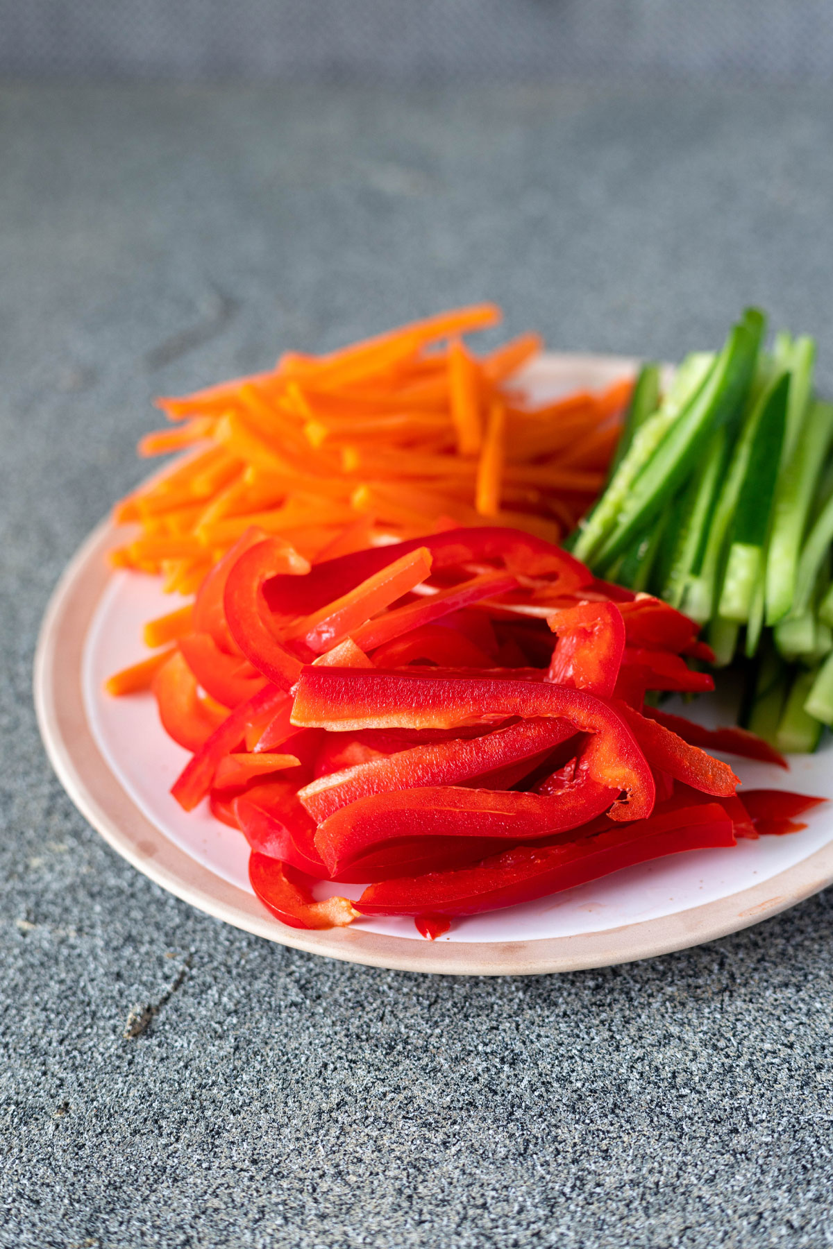 red pepper, carrot and cucumber cut on a small white plate