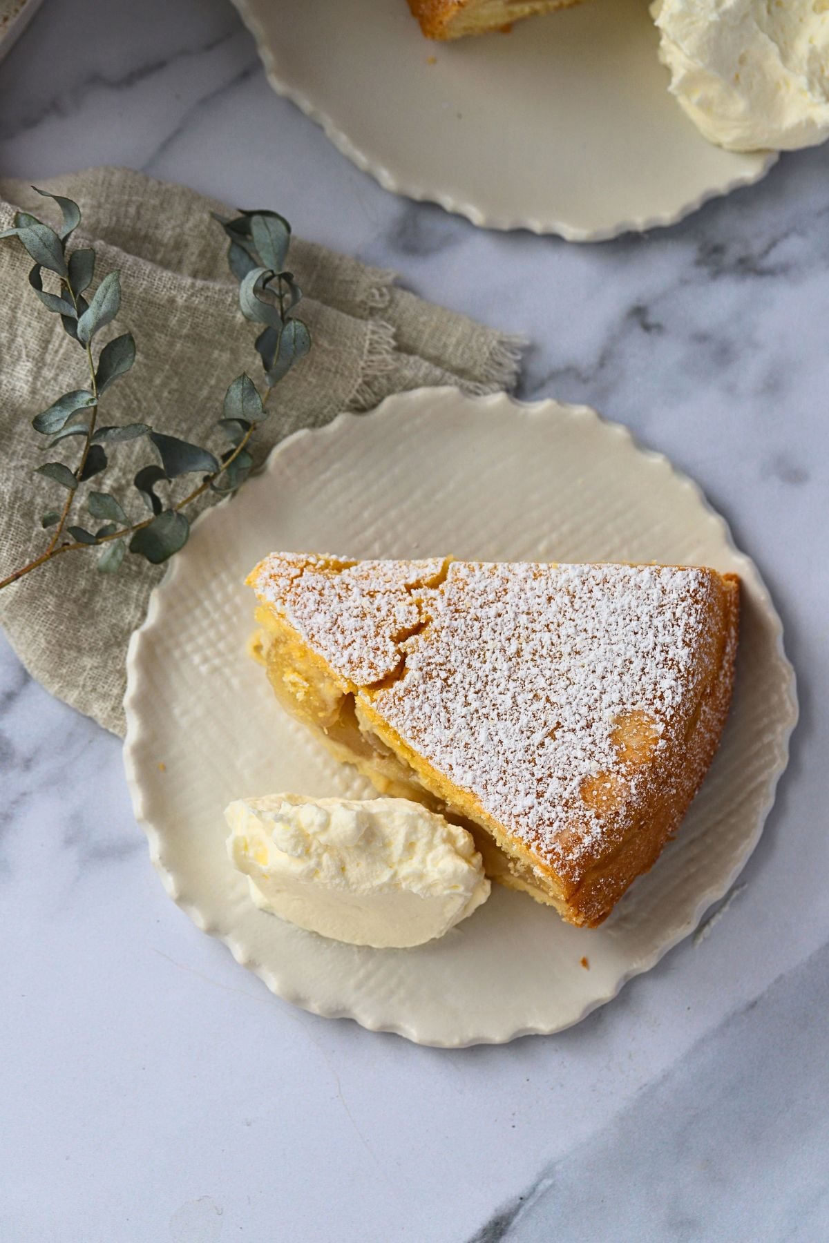overhead of apple cake on a small plate with a dollop of cream to the side of the cake.