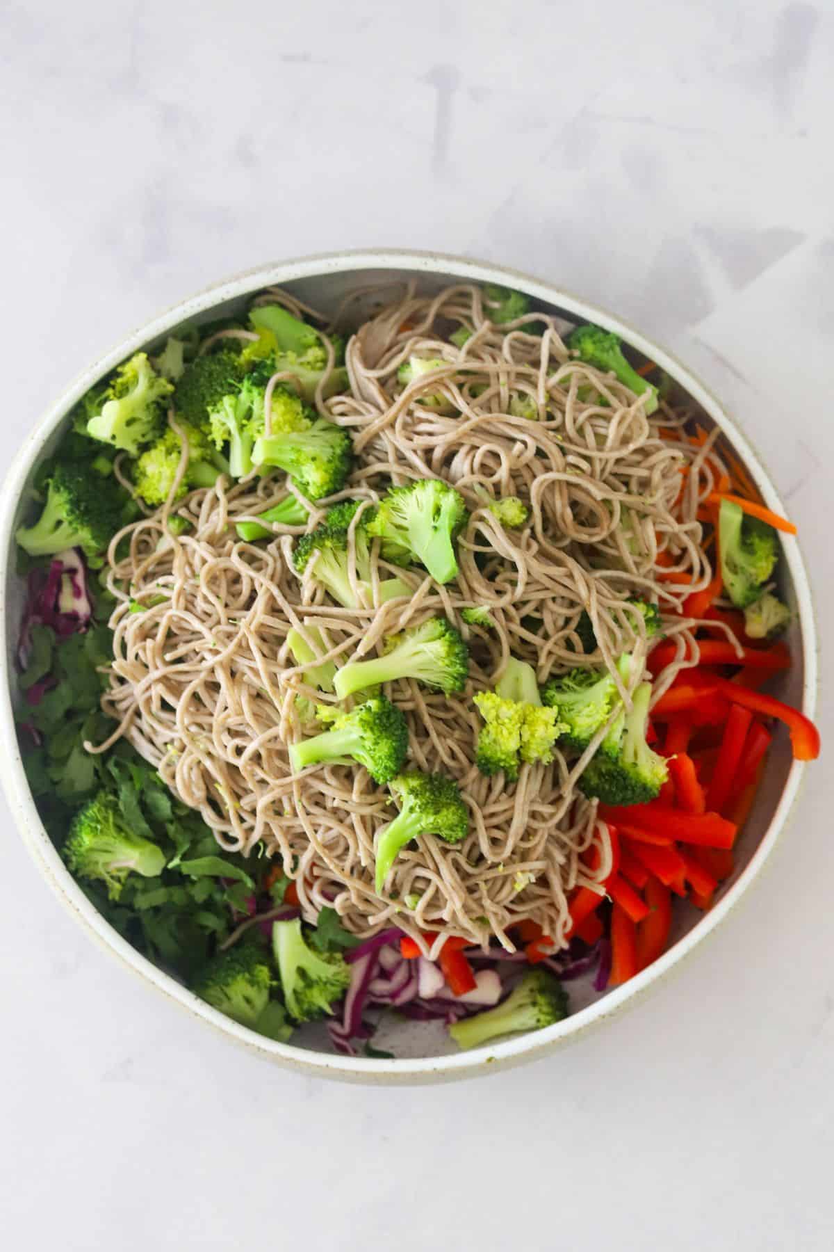 soba noodles and broccoli added to salad bowl
