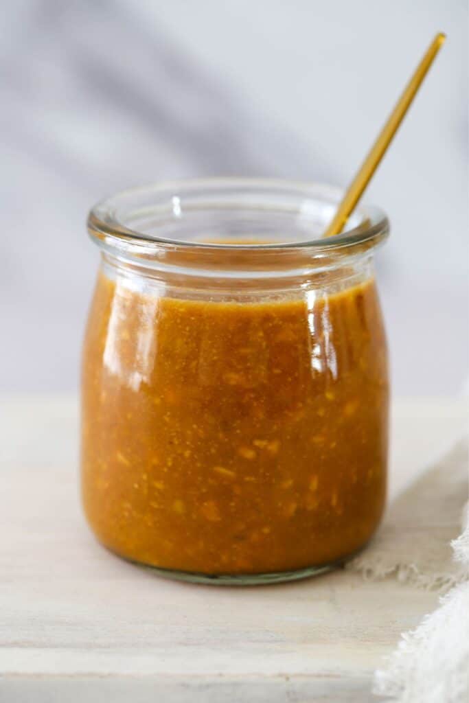 sesame peanut dressing in a clear glass jar with a spoon