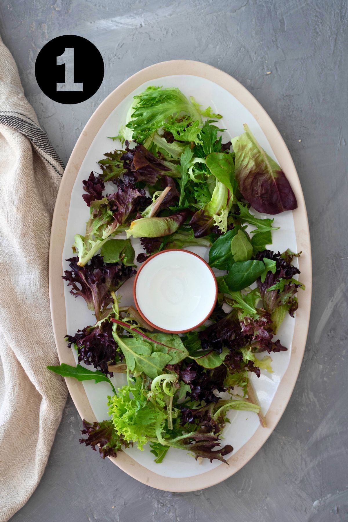 small bowl in the centre of a large platter surrounded by leafy greens.