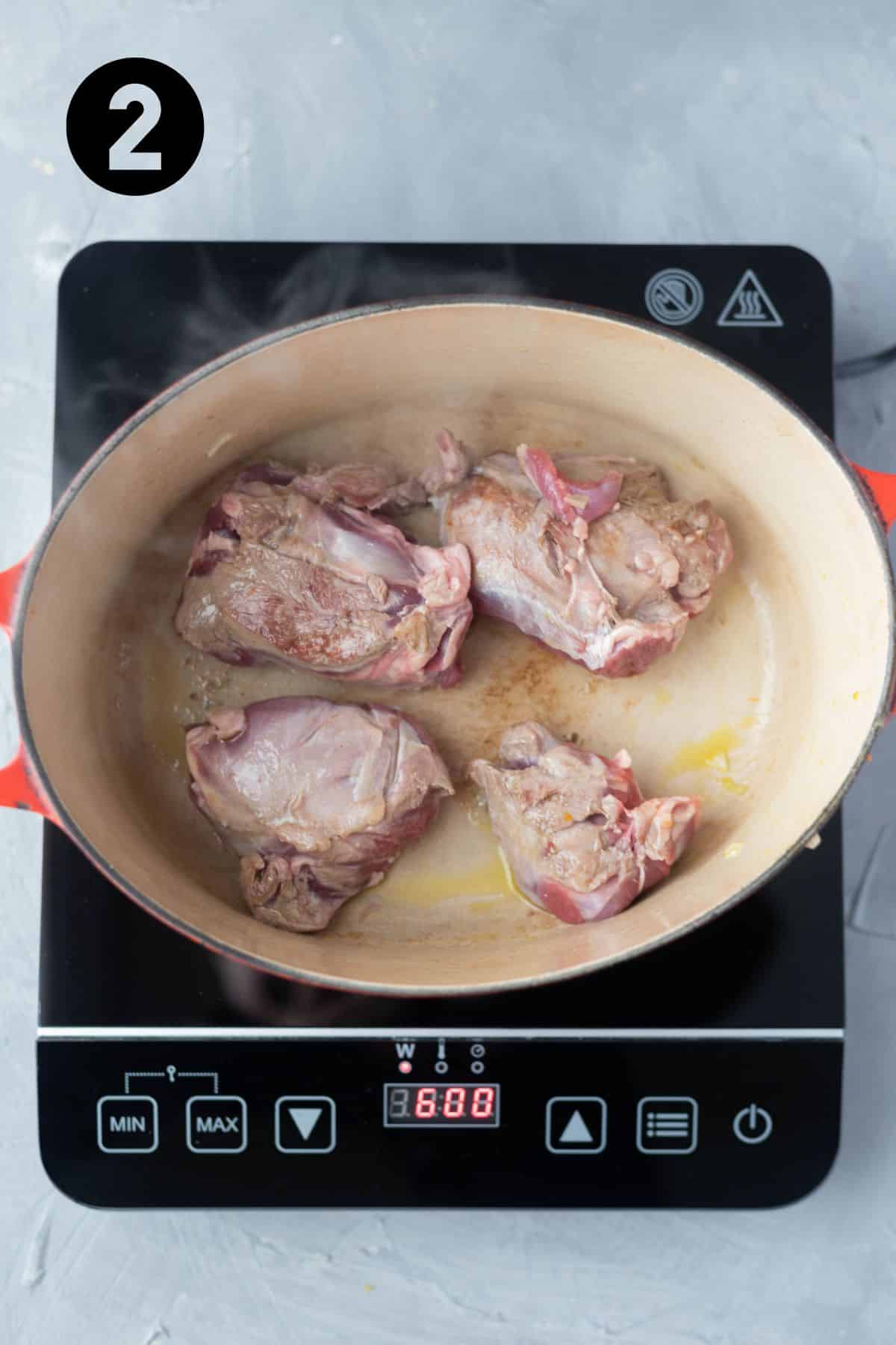 Browned lamb shanks cooking in Dutch Oven.