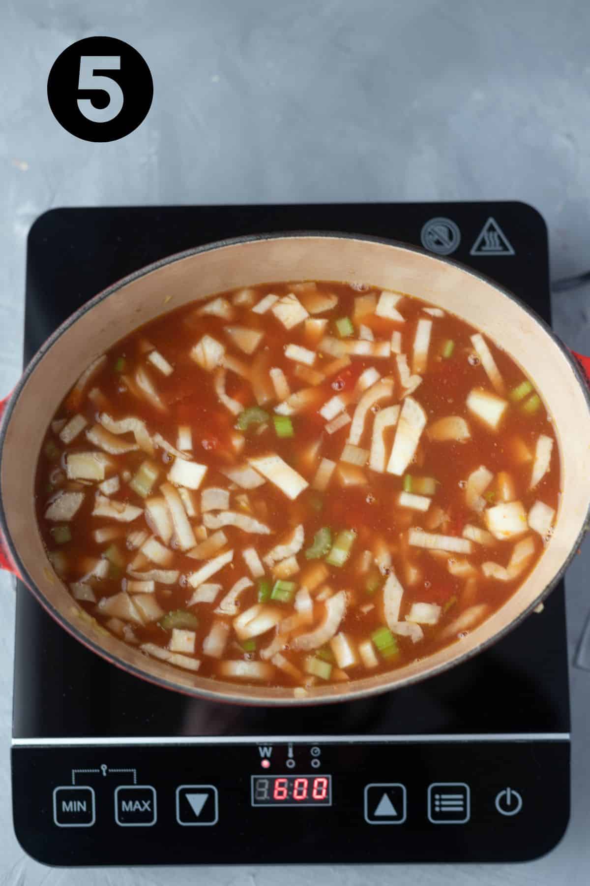 stock and tomatoes added to soup in Dutch Oven.