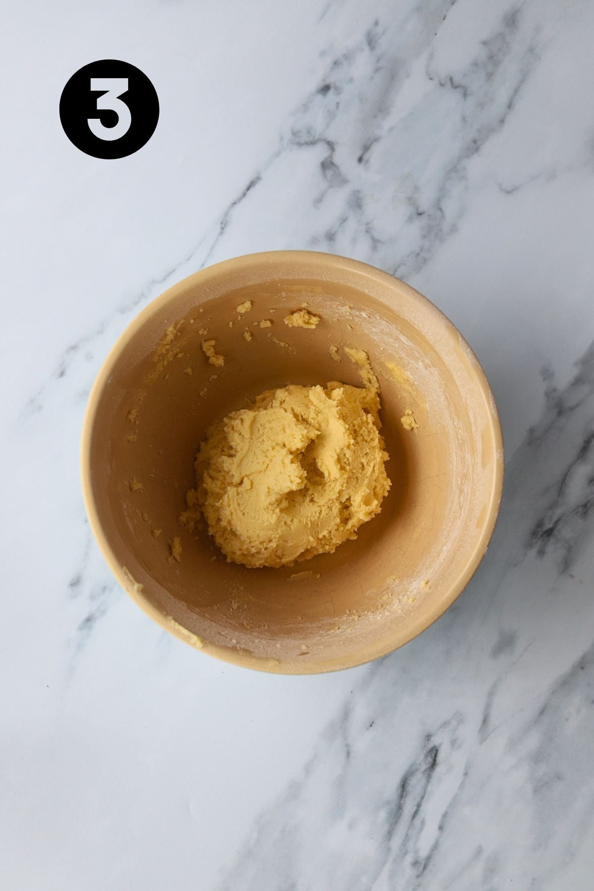 flour added to form a dough in a large mixing bowl on marble bench.
