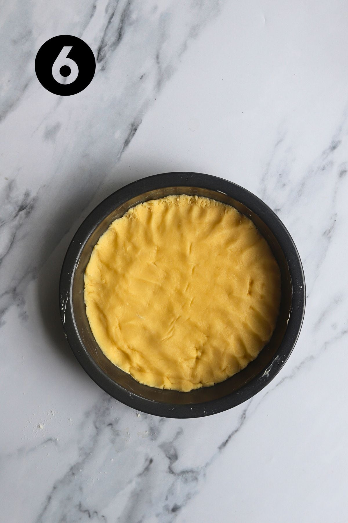 cake dough pressed into a prepared round cake tin.