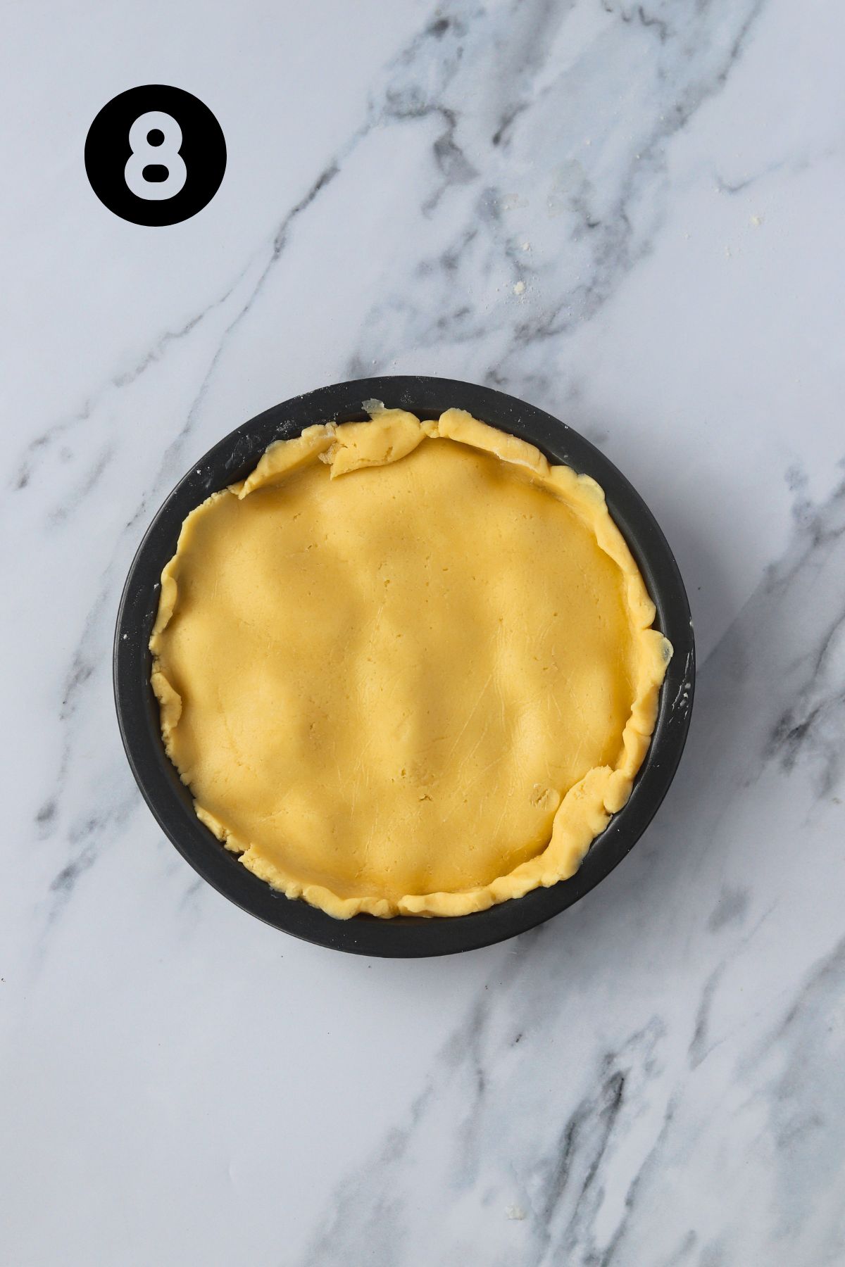 second half of dough pressed onto the top of the apple sitting in a circular pan.