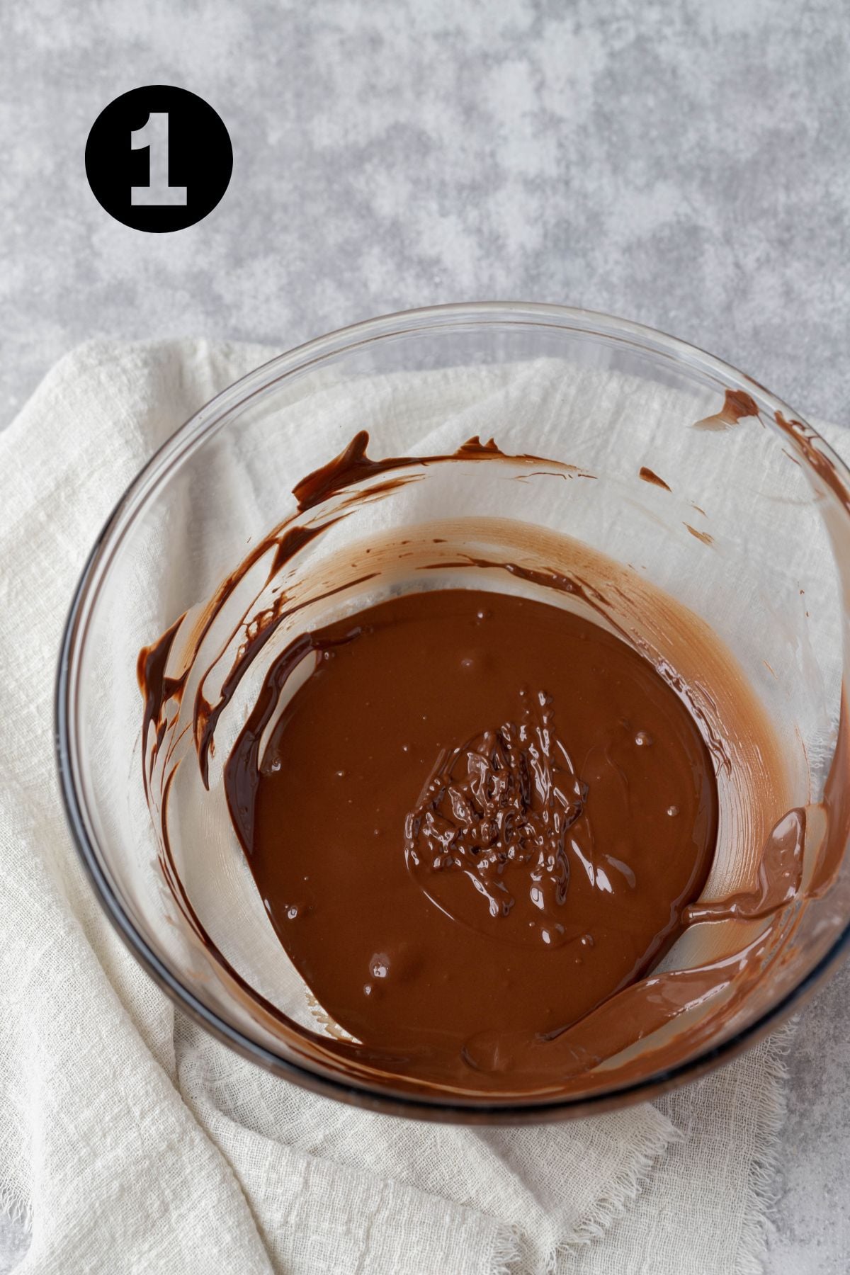 melted chocolate in a glass bowl on a linen napkin.