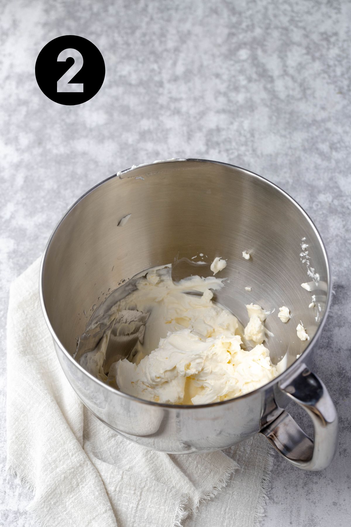 whipped cream in a stainless steel kitchen aid bowl on a linen napkin.