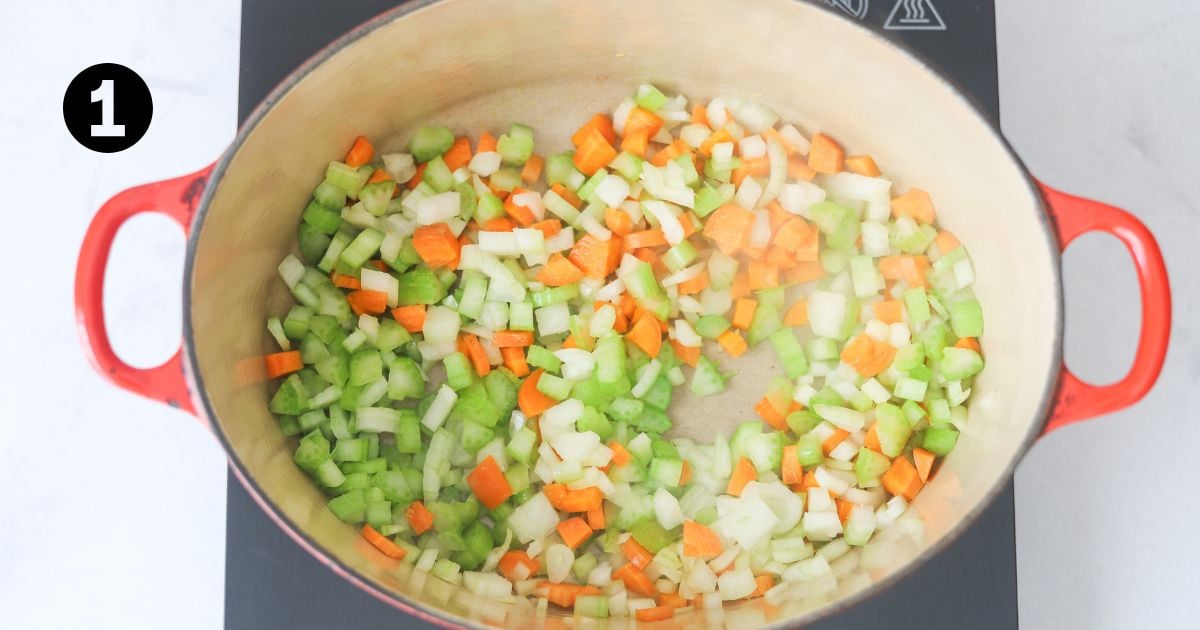 onion, celery and carrot cooking in a dutch oven on a portable stove top.