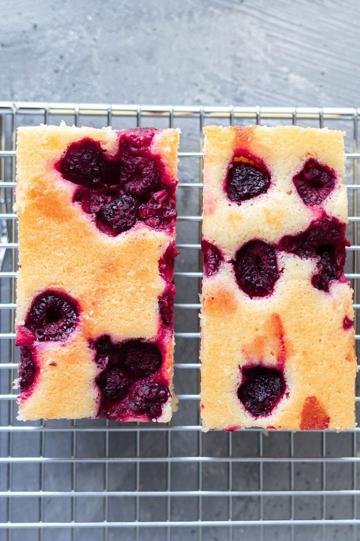 two pieces of lemon cake side by side on a wire rack.