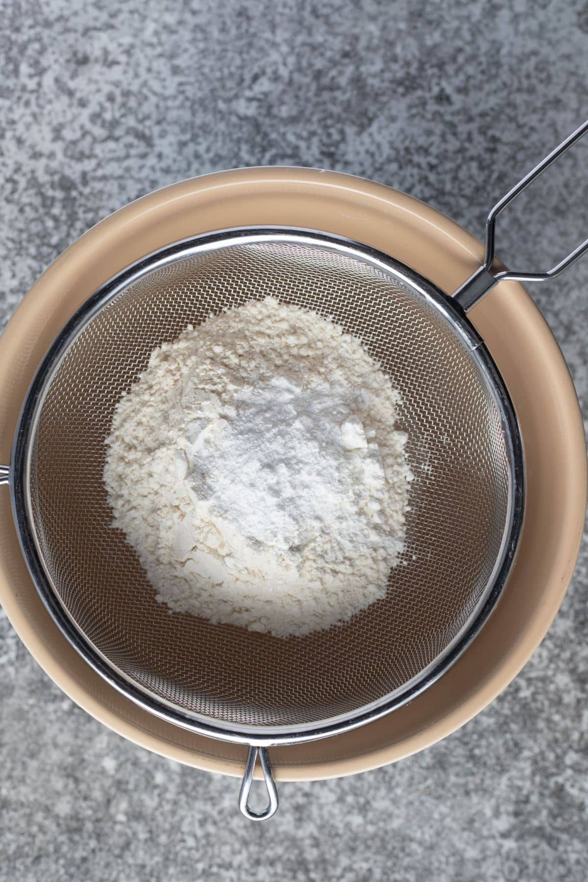 flour and corn flour in a sieve over a large bowl.