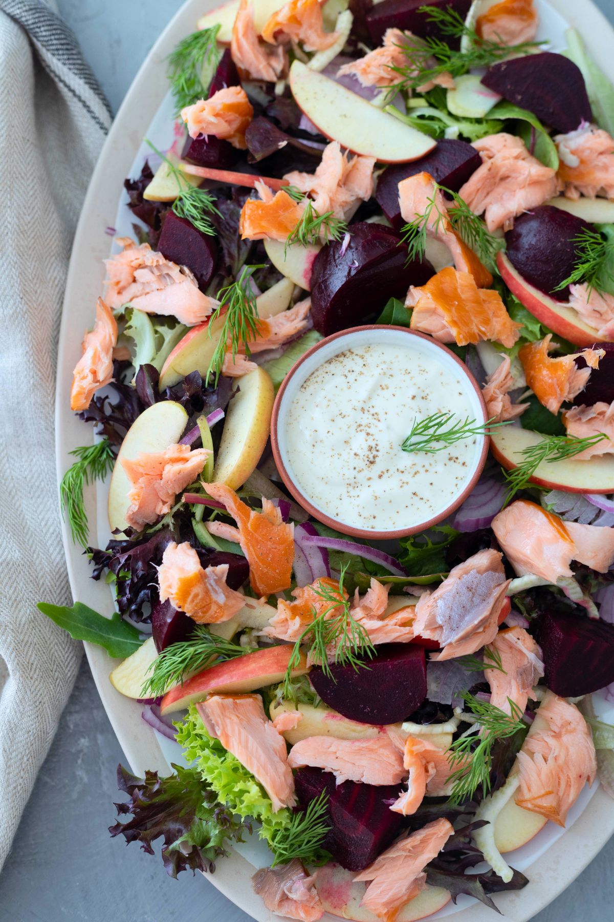 hot smoked salmon salad on a large platter. A small bowl of horseradish dressing is in the middle of the salad.
